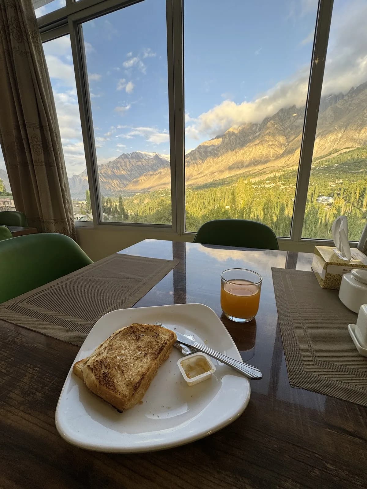 Breakfast at Hilltop Hotel Hunza with sunlit mountains through the window